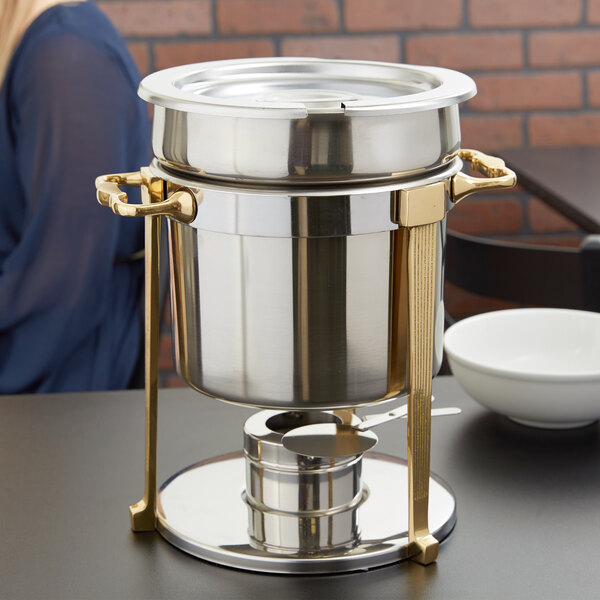 A Vollrath stainless steel soup chafer with brass trim on a counter.
