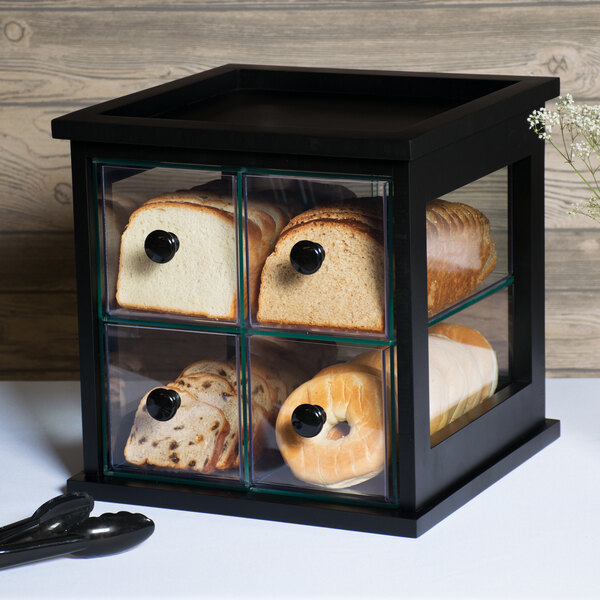 A black Cal-Mil bread box with a glass case displaying bread and bagels.