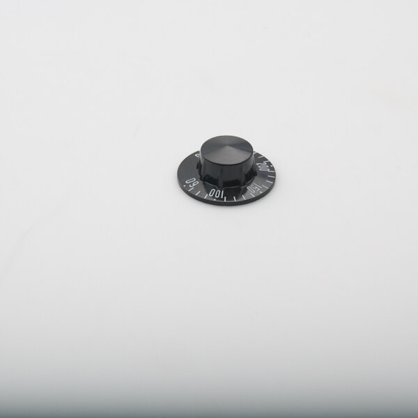 A black knob with a black dial with numbers on a white surface.