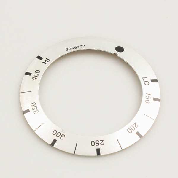 A US Range griddle dial insert with numbers on a circular silver disc.