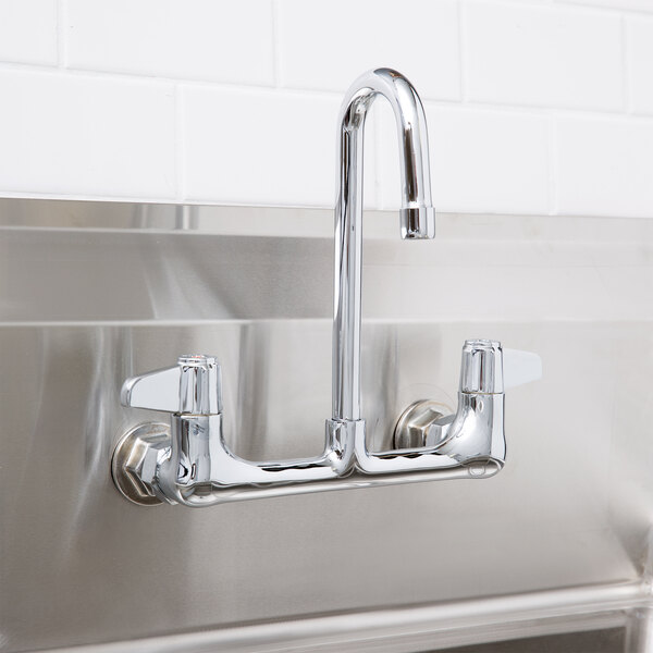 A stainless steel Equip by T&S wall mount faucet with gooseneck spout and lever handles over a sink.
