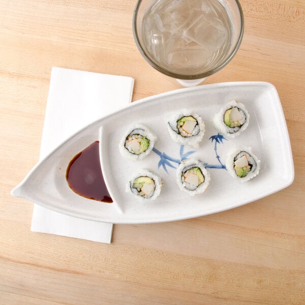 A white plate of sushi on a Thunder Group Blue Bamboo sushi boat next to a glass of water.