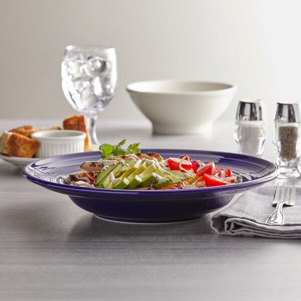 A Tuxton cobalt blue bowl filled with food on a table.