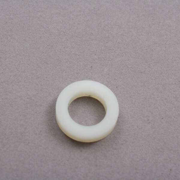 A white round washer with a hole on a grey surface.