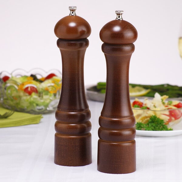 Two brown wooden Chef Specialties pepper mills on a table.