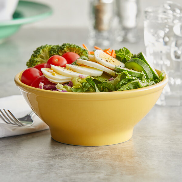 A yellow Tuxton china bowl filled with salad, eggs, and vegetables.