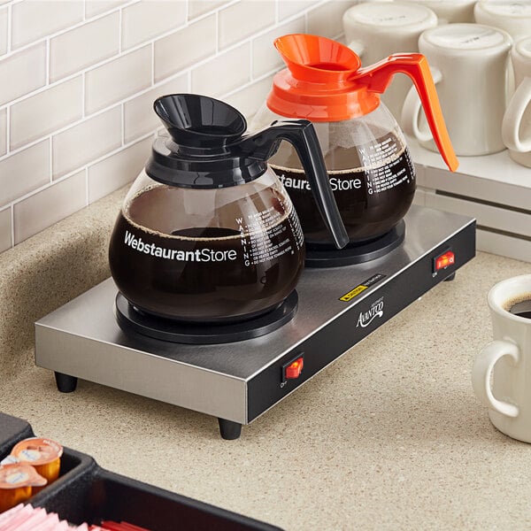 An Avantco double coffee decanter warmer on a counter with coffee cups.