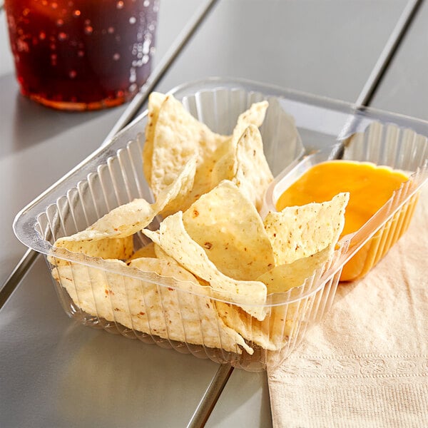 A plastic container with tortilla chips and salsa on a table.