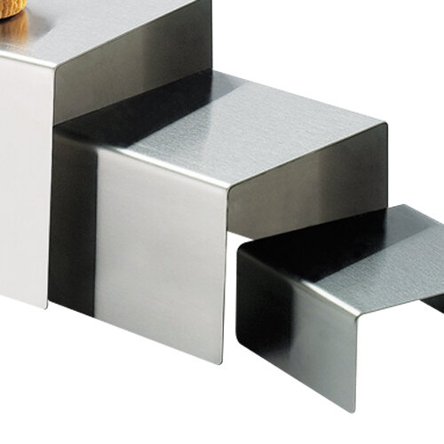 A stainless steel open square riser with a wooden object on the top step.