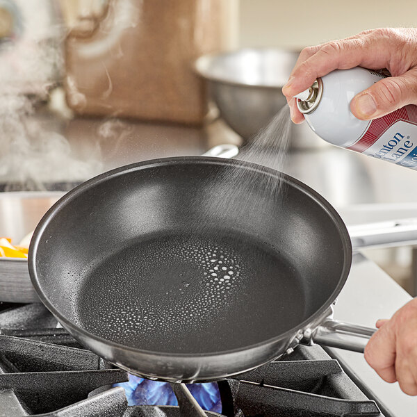 A person spraying a cooking pan with a Benton Lane all purpose release spray.