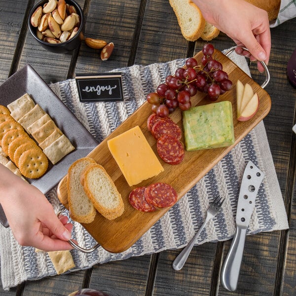 A rectangular Tablecraft acacia wood display board with food on it.