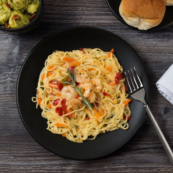 A Libbey Driftstone Onyx Satin Matte porcelain coupe plate with pasta, shrimp, and vegetables.