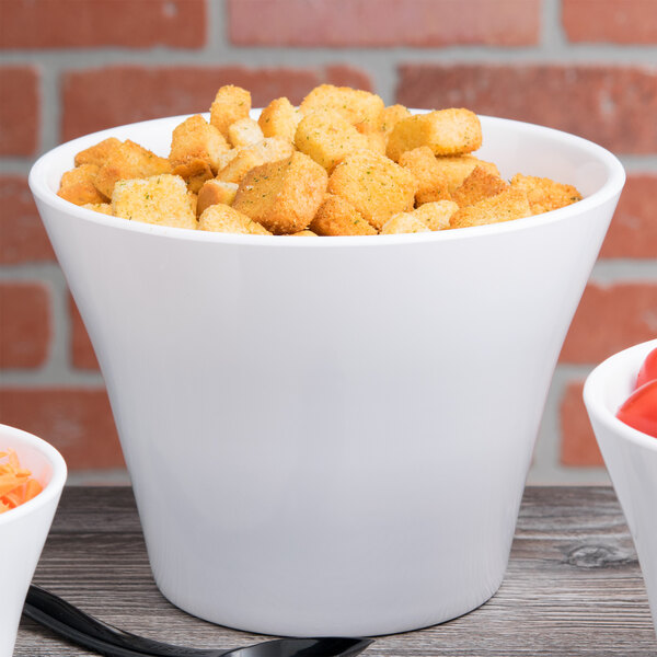 A close up of a white crock filled with croutons.