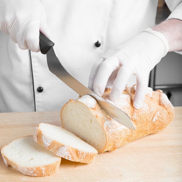 A person in white gloves using a Mercer Culinary Millennia offset serrated bread knife to cut bread.