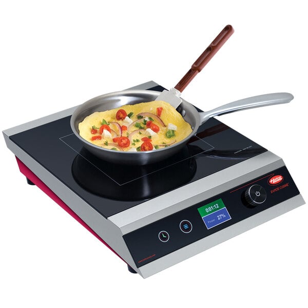 A Hatco countertop induction range with a pan of omelette cooking on it.