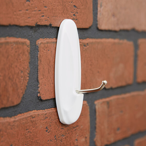 A 3M Command White plastic hook on a brick wall.