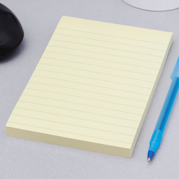 A 3M Canary Yellow lined Post-It notepad next to a blue pen on a table.