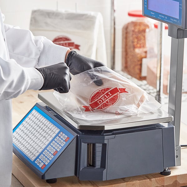A person weighing food in a Choice printed plastic deli saddle bag on a scale.