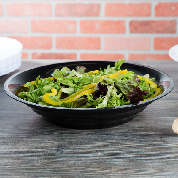 A bowl of salad with yellow peppers in a black Fineline low profile plastic catering bowl.