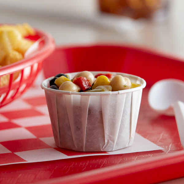 A small white paper cup of food on a red tray.