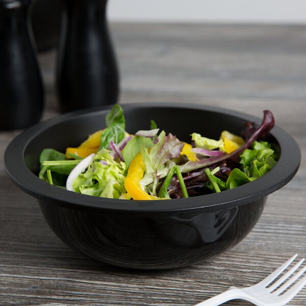 A bowl of salad with yellow pepper and lettuce in a black Fineline low profile plastic bowl.