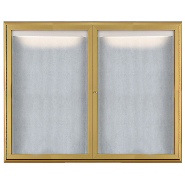 A white bulletin board with a gold frame and a window with a gold metal door and frosted glass panels.