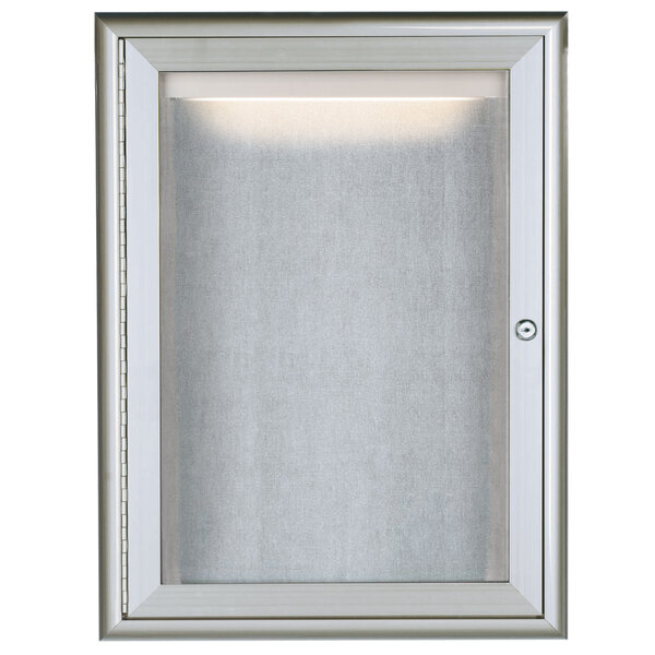A silver framed Aarco bulletin board with a white door and LED lighting.