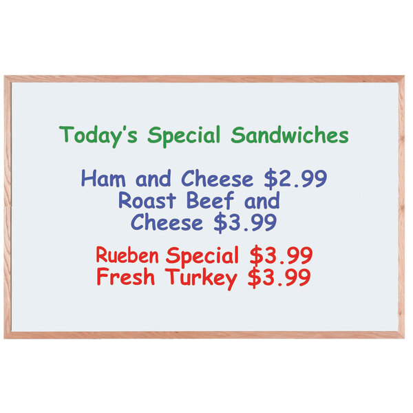 An Aarco oak frame white marker board with green text that says "Today's Special: Sandwiches"