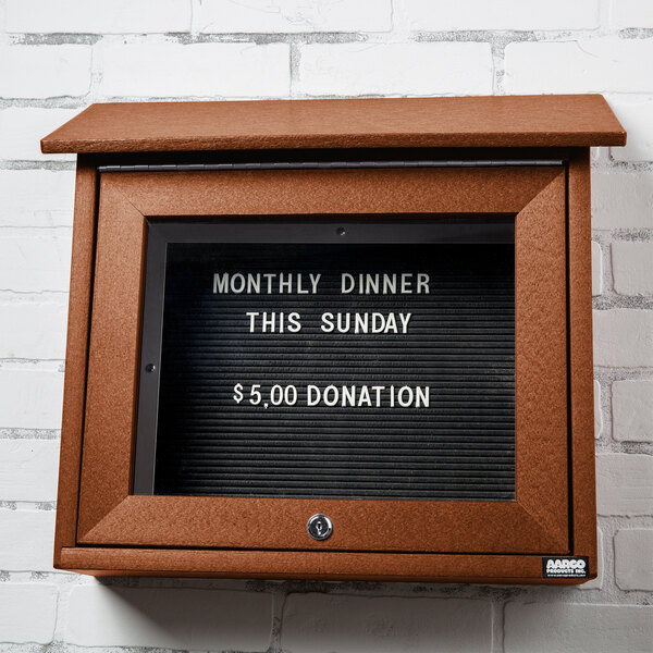 A brown Aarco outdoor message center with a black letter board displaying white text.