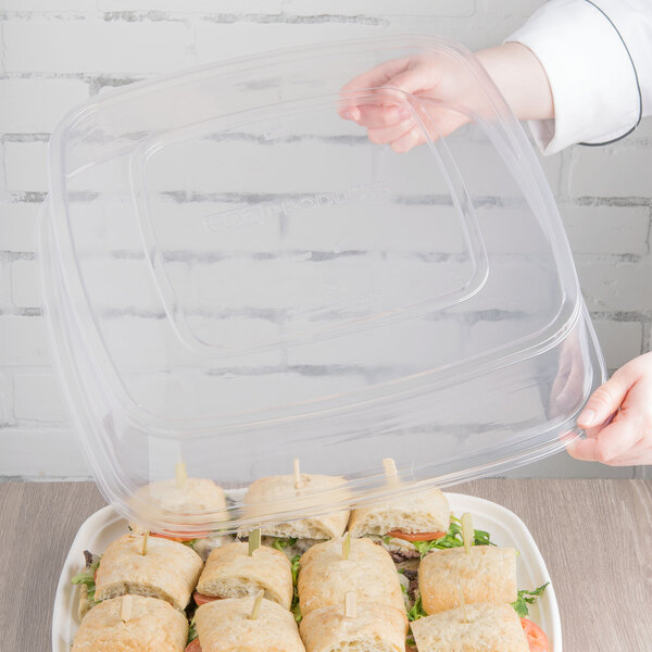 A person holding a clear plastic container with food in it.