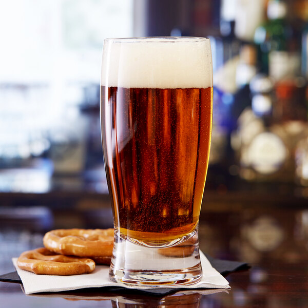 A glass of Anchor Hocking Barbary Pub beer with pretzels on a table.