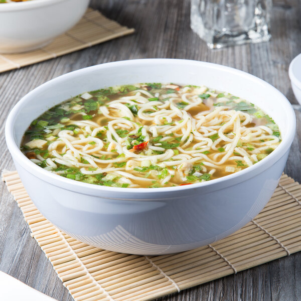 A close up of a white Thunder Group melamine pho noodle bowl filled with soup, noodles, and vegetables.
