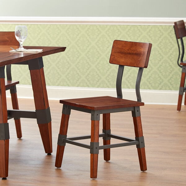 A Lancaster Table & Seating rustic industrial dining side chair with an antique walnut finish and metal frame.