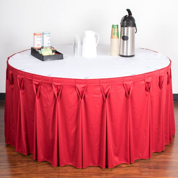 A table with a red Snap Drape table skirt and a tray of coffee cups.