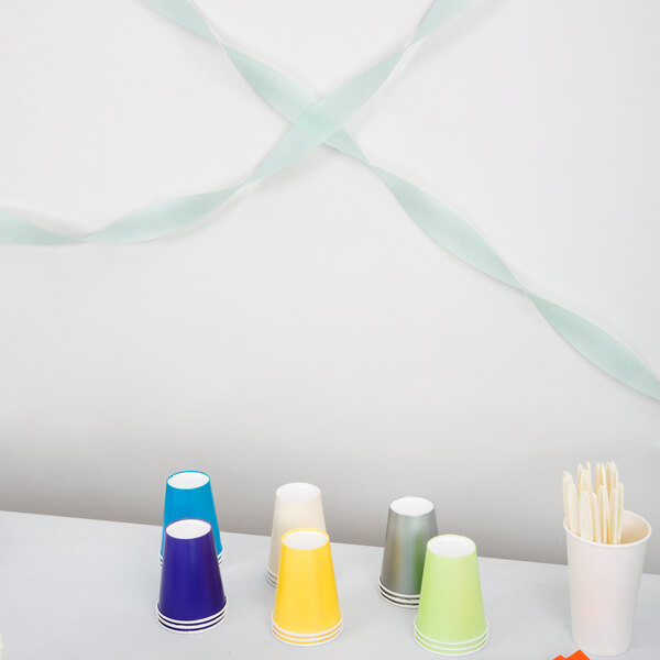 Fresh mint green Creative Converting streamer paper on a table with cups and other items.