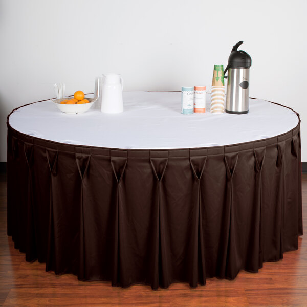A table with a brown Snap Drape Wyndham table skirt with Velcro clips on it.