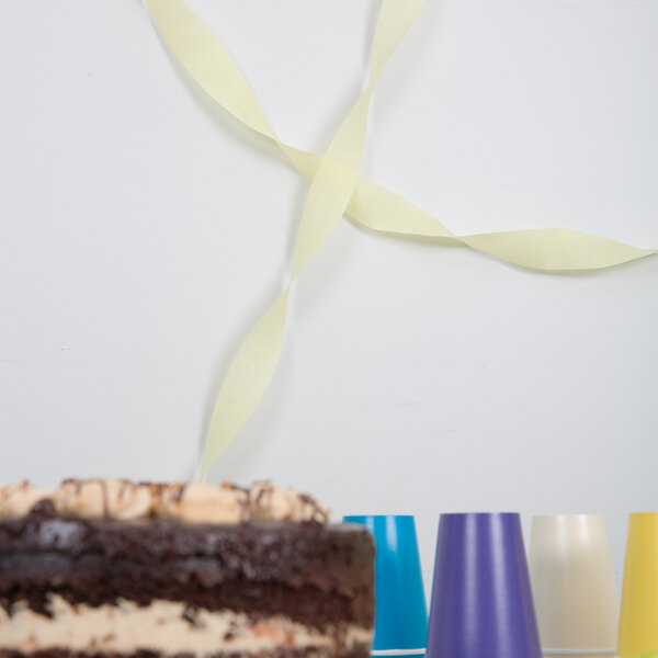 A chocolate cake with a yellow ribbon made of Creative Converting Mimosa Yellow Streamer Paper on a white surface.