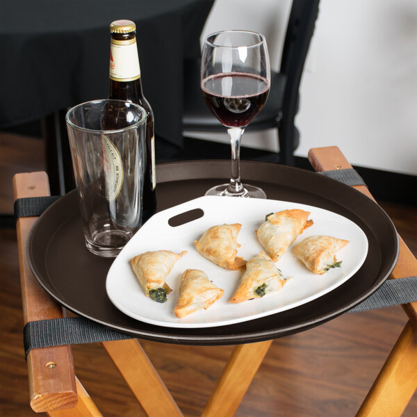 A plate of food and a glass of wine on a Cambro non-skid serving tray.