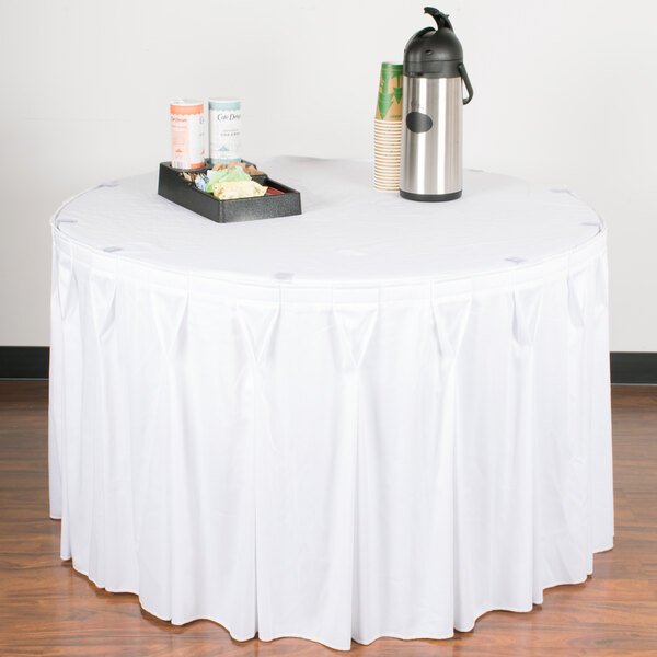 A table with a white Snap Drape table skirt and a tray of food.