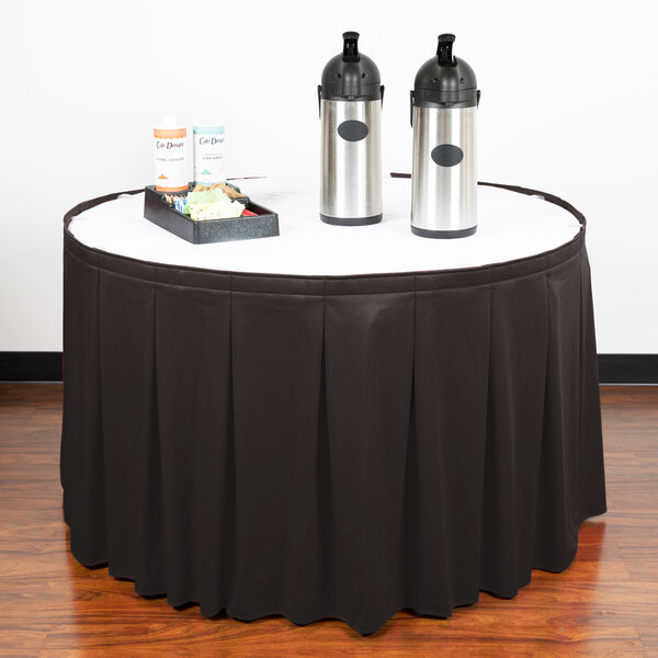 A black table skirt on a table with two metal containers on it.