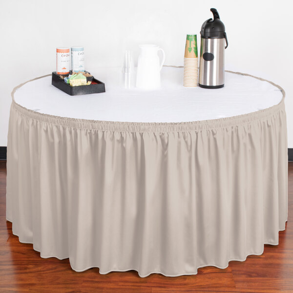A table with a Snap Drape silver cloud shirred pleat table skirt on it and a tray of coffee cups.