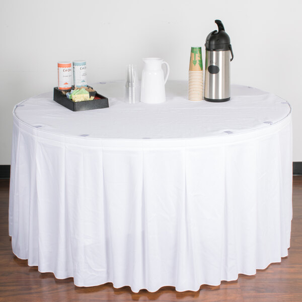 A table with a white tablecloth and a Snap Drape white continuous pleat table skirt with Velcro clips.