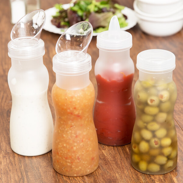 A group of frosted clear plastic salad dressing bottles with lids on a table.