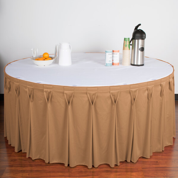 A table with a Snap Drape Sandalwood table skirt with a bow tie pleat on it.