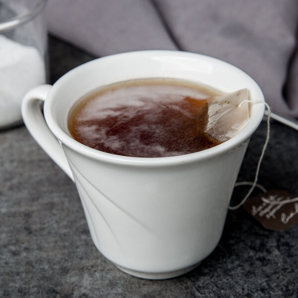 A white Libbey tall porcelain tea cup with a tea bag in it.