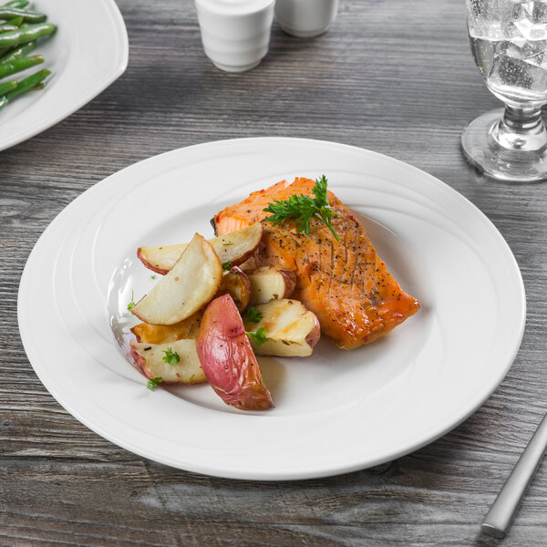 A Libbey white porcelain plate with salmon and potatoes on it.
