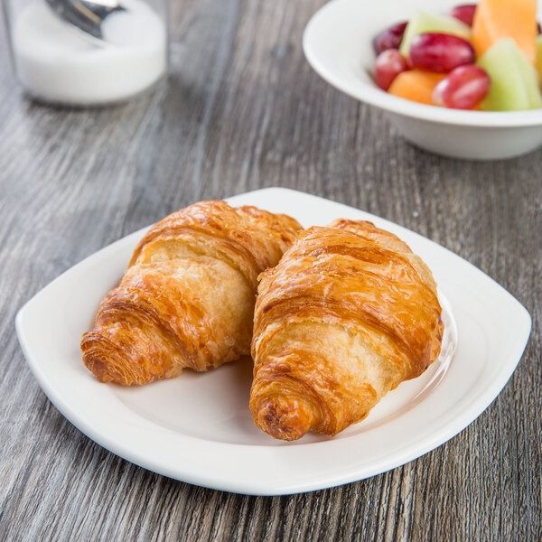 A Libbey square white porcelain plate with two croissants and fruit.