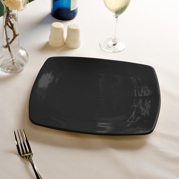 A black square CAC stoneware plate with a fork on it.
