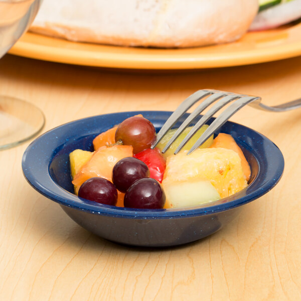 A Carlisle Dallas Ware blue melamine fruit bowl with a fork in it filled with fruit.
