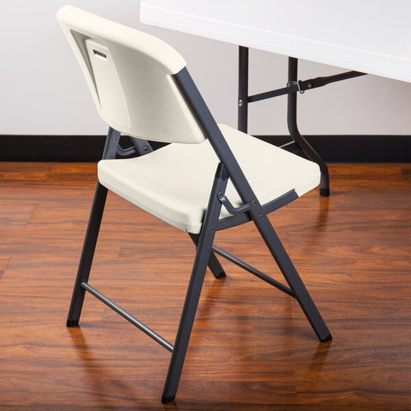 An almond Lifetime contoured folding chair under a white table.